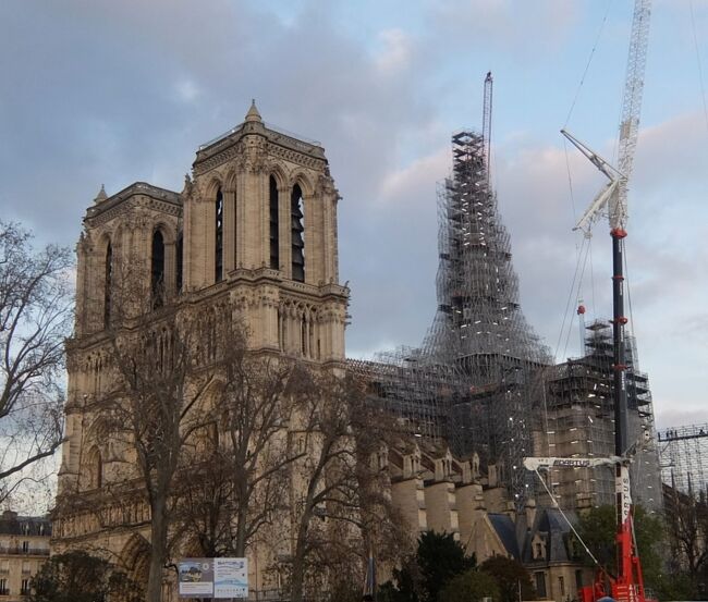 2019年4月の火災で失われたノートルダム・ド・パリの尖塔は以前のままに再建され、クリスマス前の12月6日には頭頂部に十字架が設置された。<br />さらにその10日後には十字架の上に金の雄鶏が戻された。<br />これで4年8ヶ月ぶりに、焼失前の姿が蘇ったことになる。<br /><br />とは言っても、周囲に工事用足場が組まれているので、その実像を目にすることはまだできない。それでも目を凝らして眺めれば、かろうじて工事用パイプの間から十字架の形が認められる。<br /><br />今後は屋根材を組み立て、鉛の皮膜や装飾を施し、さらに内部の修復や復元作業を進めて、2024年12月8日の一般公開が予定されている。<br />当初の計画であった2024年4月の再開も、パリオリンピックまでにという願いも叶わなかったが、コロナ下の制約があったことを考えれば称賛に値する進捗ぶりだと思う。もちろん、この世界的な名所に寄せられた多額の寄金が裏付けとはなっているのだが。<br /><br />大聖堂前広場の地下には「エスパス・ノートルダム　Espace Notre-Dame」と名付けられた展示施設が設けられ、主に技術的な面の解説が用意されていて、修復工事の一部始終をつぶさに知ることができる。<br /><br />世界の各地で軍事侵略による破壊と殺戮が続き、あるいは自然災害による甚大な被害が報じられる中で、人びとを絶望的な気持ちにさせたあの火災からの復活は、何はともあれ喜ばしい出来事であることに間違いない。<br /><br /><br />