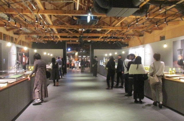 ニッカウヰスキー蒸留所のフリーゾーンにはレストランの他にも展示室や資料館などもある。お昼を食べ終えてから、それ等の施設を見学することにした。車でやってきてレストランで食事し、その後、この資料館にやってくる人も多い様だ。工場敷地の緑地には余り人影を見なかったが、この館内にはかなりの人がいる。皆感心をもってニッカの歴史、ウイスキーの品種、製造方法などを熱心に見ている。一番の人気は利き酒コーナーで、ワンショット３００円から５００円程度で、ニッカの高級ウイスキーの試飲ができるのだ。<br /><br />自分も試しにワンショットを試飲してみたが、先ほどお昼に飲んだばかりで、それ程びっくりする程の美味しさは感じられなかった。矢張りビールにしてもウイスキーにしても、先刻のように何か食事とか摘まみとかを一緒にして飲むほうが、より酒にしても食事にしても味わいが深まるみたいだ。<br /><br />さて資料館を見終わってこれから又余市駅に戻るのだが、ここにはタクシーがいない。自分の足でぐるッと工場外壁に沿って駅まで歩くのは大変だ。フリーゾーンと蒸留工場との間にはバーが下ろされていて、一般の通行が禁止されている。見張り役の係員に事情を話し、工場を横切って駅まで行きたい旨を話した処、係員はどこかに電話連絡していたが、OKが出た。助かった。ステッキをついていたのが功を奏したのか・・。<br /><br />さて、これで真っすぐ工場内敷地を横切って駅まで行ける。ぶらぶら工場内を歩き、駅に面する出口に向かった。如何にも欧米風の工場建物レイアウトで、外国へ来たような感じだ。途中工場見学ツアーの２０数人のグループと鉢合わせしたが、皆さん熱心に案内人の説明を聞いている。何年か前にNHK朝ドラで放映されたマッサンとその妻の情景を思い出した。<br /><br />奥さん、エマ役を演じたケートはその後どうこでどうしているか・・。朝ドラが終わった後、テレビで見ることもなくなったが、米国へ帰ってしまたのか・・。二人の間には子供が生まれず、養子をもらった。二人の子供たちは、今ではもう自分と同じ位の年齢になっているだろう・・。マッサン亡き後、工場を引き継ぎ、立派にやっているだろうか・・。そんなことを思いながら出口に向かった。