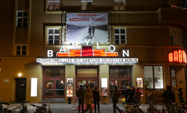 映画『ベルリン天使の詩』冒頭で天使たちが腰掛けていた戦勝記念塔（Siegess&#228;ule Berlin）の女神像、思いつきで塔に入ったところ、運良く映画の天使たちと同じ視線でベルリン市街を眺めることができた。<br />そして、ベルリンの映画館で度々『ベルリン天使の詩』を上映しているバビロン座（Kino Babylon Berlin）、訪れてみると専属のオーケストラやオルガニストを抱えた映画館で、今となってはとても希有な存在。劇場オルガンは現存する数少ない逸品とのことである。<br /><br />○ 戦勝記念塔 映画『ベルリン天使の詩』の象徴的な女神像<br />○ 映画『ベルリン天使の詩』をベルリンで観られるトーキー映画館<br />○ バビロン座の上映作品『カリガリ博士』『モダン・タイムス』<br />○ バビロン座のキノオルゴール（kino-orgel）/劇場オルガン（Theatre organ）<br /><br />映画『ベルリン天使の詩』のポスターやジャケットにはこの戦勝記念塔の女神の肩に腰掛ける天使の姿が写っている。幾度も目にした天使が座る女神像のそばまで行けることを今回初めて知った。遠目に見れば高く細長い塔である、まさか塔の先端まで登れるとは思いも寄らなかった。<br /><br />塔を遠くから眺めると台座が彩り豊かな回廊になっており、人影が見えることがある。あそこまでは行けるのだなと考えながら塔の入口をくぐった。入場料は現金のみの支払いで4ユーロ、今時のベルリンで現金払いとは珍しい。<br /><br />中に入ろうと思ったきっかけは、何度もティーアガルデンをサイクリングしていたので、ついでとばかり気軽に中に入ってみただけだった。この気軽な感覚があとで自分の脚に悲惨な状況を引き起こしてしまった。<br /><br />入場すると1階部分はちょっとした博物館になっており、ドイツ各地の戦勝記念碑的な建造物のパネルや模型が並んでいる。ちなみにベルリンのこの戦勝記念塔は19世紀のドイツ帝国建国につながる戦いにおけるプロイセンの勝利を記念して1872年に建てられた。<br /><br />このドイツの戦勝記念碑関係は堅牢で立派なものが多く見応えがある。ライプツィヒにある「諸国民戦争記念碑（V&#246;lkerschlachtdenkmal）」などはとても立派なものだったから、こちらの戦勝記念塔にももっと早く訪れるべきだったのだ。<br /><br />そして、展示室を抜けると階段があり、そちらを登ると台座にたどり着く。この台座にはプロイセンの大勝利を描いたレリーフがあり、これが塔をぐるりとまわって飾られている。回廊状の台座を歩きながら、このレリーフを眺められるので、1階の博物館にあるキャプションパネルの説明書きを思い出しながら眺めた。<br /><br />そして、更に塔の頂上を目指して階段を登る。このらせん階段はなんと285段もあり、なかなかハード。高さは70m近くあるのだから当たり前である。気軽な気持ちで入館したものの、この階段のおかげで翌日はふくらはぎがパンパンになってしまい、その痛さたるや・・・。<br /><br />しかし、さすがに頂上の展望台からの眺めは素晴らしい。ティーアガルデンの真ん中に位置するので目の前を遮るような建造物はまったくない。塔を中心に放射状に伸びる道の先には東西南北のベルリンの街が拡がっている。<br /><br />ポツダム広場方面の通い続けたベルリン フィルハーモニーのコンサートホールや州立図書館 ポツダム館が金色に輝いて見える、周囲の景色の中でも、とりわけ映えているのが、ちょっと嬉しい。<br /><br />詳細はコチラ↓<br />https://jtaniguchi.com/siegessaule-kino-babylon-berlin/