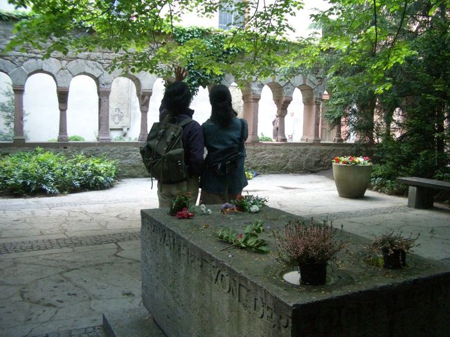 左の中ほどの扉から外に出ると小さな中庭で、12世紀の小さな回廊があります。<br />この回廊、柱のひとつひとつのデザインがすべて違い、これは当時の豊かさを表したものだそう。<br /><br />その奥には詩人・フォーゲルワイデ（1230年没）のお墓が、彼の有名な詩集『樅の木の下に』にちなみ、樅の木の下に造られています。<br />墓石の四隅にある小さな水のくぼみは（花がそなえてありますが）小鳥の水飲み場で、フォーゲルワイデの名前がそんな水飲み場の意味があり、墓石にもつけられているそうです。<br />