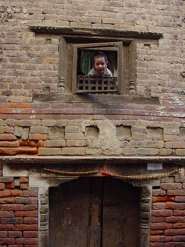 窓からのぞく少女（パタン）<br /><br />●ネパールの建物は煉瓦と木材の組み合わせです。<br />