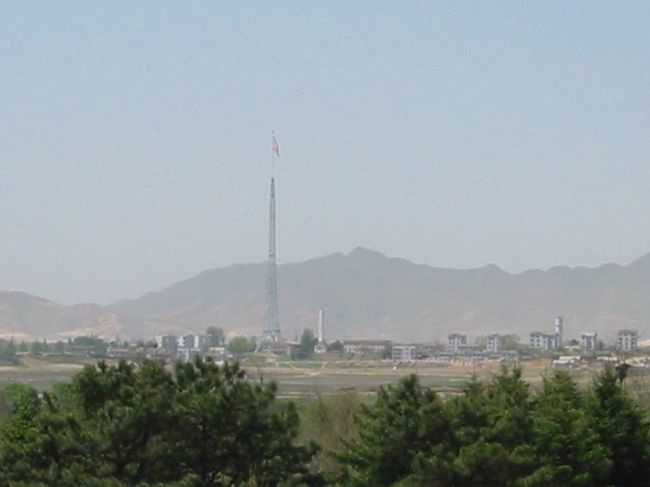 いよいよ板門店へ。バスは｢自由の家｣のすぐ前にとまる。<br />ガイドに２列に並ぶように言われ、訪問者用の展望台に向かう。ここから、メーンの｢軍事停戦委員会の本会議場｣、｢板門閣｣(北朝鮮側の訪問者用展望台）、北朝鮮の｢宣伝村｣などが見える。板門閣には大勢の人が。ガイドによると、北朝鮮の軍高官の家族らしい。<br />写真は、北朝鮮の宣伝村で、「キジョン洞」という名前。無人で、建物は張りぼてらしい。<br />中央に見えるのは、巨大な国旗掲揚塔で、高さ約１６０?。