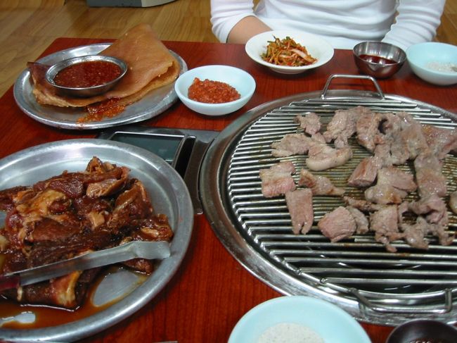 生カルビのほか、味付けカルビ（テジカルビ、写真左下）と豚皮（コッチル、同左上）も注文する（いずれも１人前）。<br /><br />まずは生カルビ。噛めば噛むほど肉汁が出てくる。単純ではあるが、図太い旨みがバズーカ砲のように口内を襲う。モチ豚と比べると肉は硬いが、この弾力。歯茎が喜んでいる。<br />脂も美味なり。<br />次はテジカルビ。<br />ヤンニョムにつけ込んでいるので、味がしっかり浸みており、やや肉が柔らかくなっている気がする。<br />コチュジャンにつけ、サンチュに巻いて食べる。<br />ううう、いける。<br />こちらは、肉の複雑な味があふれ出すのを、チシャがしっかりくるみ、全体的に優しい味になっている。<br />豚の赤身はこんなにおいしかったのかと、目を開かされる。<br />アバラ骨についた肉や脂身を、歯で刮ぎながら食べるのも、動物になったようで気持ちいいものだ。<br />肉の焼ける香りもいい。<br /><br />最後にコッチル。<br />噛み心地がたまらない。<br />お餅やゴムを噛んでいるような、硬からず、柔らからずの感触。<br />噛むたびに、甘みがあふれ出る。<br />あまり噛みすぎたので、ややあごが疲れた。<br /><br />麦酒を２本のみ、高菜味噌汁をサービスでもらって、計２６０００㌆。安すぎます。<br />
