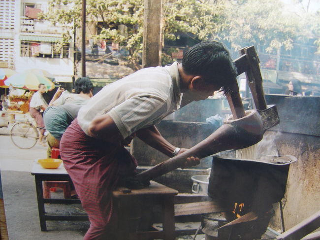 練りあがった物を木の圧縮機に入れ,熱湯の中へ押し出している.