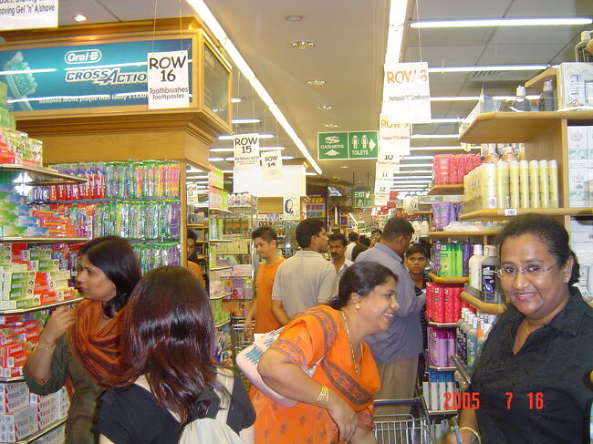 続いてムスタファセンター（ディスカウントストアのような店。様々な物が売られており、２４時間営業）へ。<br />（左から２番目の後ろ頭が私）<br />所狭しと並ぶ棚や商品の間に、これまたたくさんの買い物客がひしめいています。<br />シャンプー、リンス、ボディーソープを購入します。