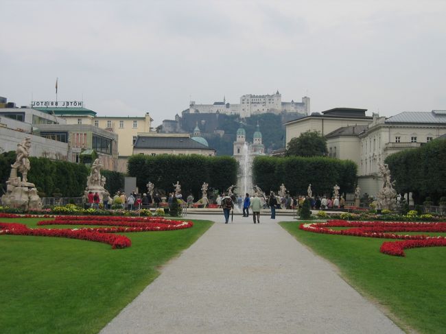 旧市街方面にバスで向かう。モーツァルトとサウンドオブミュージックの街で有名だが、遅ればせながら（かなり遅いが。。。）最近、サウンドオブミュージックを見ることがあり、その影響から、そっちメインで。ツアーがあったのだが、時間の関係から断念。自力で回ることに。<br />撮影で使われたミラベル広場とその向こうの山の頂に見えるホーエンザルツブルグ城塞。<br />丁寧に手入れされた花と芝生が素晴らしい。