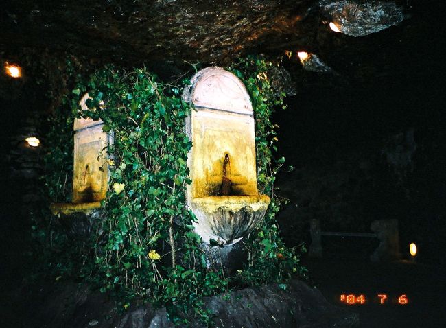 ワインの湧き出る泉や、半ば地に沈んだ巨大な古代の王の頭像の演出などは、「地球の歩き方」で前に読んで覚えていたとおりでした。ペットボトルにワインを汲んで飲んでいる人がいたので、私も手ですくって飲んでみました。確かにワインです。昼食をとる暇がなかったので元気づけに何度かすくって飲んでみました。私もなにか汲むものがあれば、もっと飲めたのに残念です。巨大な王の頭像は、「地球の歩き方」に写真がありますが、自分のカメラでも撮ろうかと迷いました。迷いつつも結局、そのまま先に進んだら、係員らしい人が現れ、足元にあった明かりのカンテラを次々と見学者に配りだしました。もちろん、私にもくれました。私はやっぱり王の頭像の写真を撮ろうと思って、一人、来た道を戻ってみたら、あたりがさっきより異様に暗いことに気付きました。そういえばさっきの係員は、配って余ったカンテラを持ち帰っていました。<br /><br />いやな予感を覚ながらワインの湧き出る泉のところまで戻ってみたら、うそーっ！　さっきとうってかわって、あたりは真っ暗です。うそでしょ、うそでしょーっ、と心の中で何度繰り返しても、事態はかわりません。なんと、係員は、進路を照らしていた明かりを、みんな持ってかえってしまったのです！<br /><br />いやはや、まいりました。すっかりまいりました。何しろ、たった今、自分が来た方向がどっちだったか、それすらわからなくなってしまうのですから。暗闇とはかくも恐ろしいものだったのですね。しかも私は方向音痴なので、自分の勘をあてにすることができません。命綱のたった一つのカンテラは、私のほんの手元しか照らさないため、この弱い明かりでは、道がどこへ続くのか、先が見えません。方向音痴だからか、岩の形や展示物で方向の見当をつけることもできません。真っ暗闇でほとんど手探り状態なので、歩いている道の壁がカンテラに照らされただけで、行き止まりかとあせってしまいます。そのうちにだんだん道が狭まってきて、人一人がやっと通れるほどに狭くなってきたときは、今度こそ行き止まりかと本当にびくびくしました。まさしくラビリントス、迷宮の名にふさわしくなって、泣けてきました。<br /><br />とはいえ、いざとなったら他の見学者の後をずっとくっついていく、という手もありました。ワインの泉のところまで戻れば、さきほどいた親子連れはまだワインに舌鼓を打っています。でも、すぐには動きだしそうにありません。あからさまに頼りにしてます、って態度を見せるには、まだ、私のなけなしのプライドが邪魔をしました。なので、まずは一人でなんとか出口に向かおうと思いました。だけど、もしこのまま閉館の19時まで出られなかったらどうしよう。<br /><br />（写真は、ワインの湧き出る泉です。手ですくってワインを飲んだら、手のひらでワインが跳ねて、白いTシャツにシミがついてしまいました（泣）。）