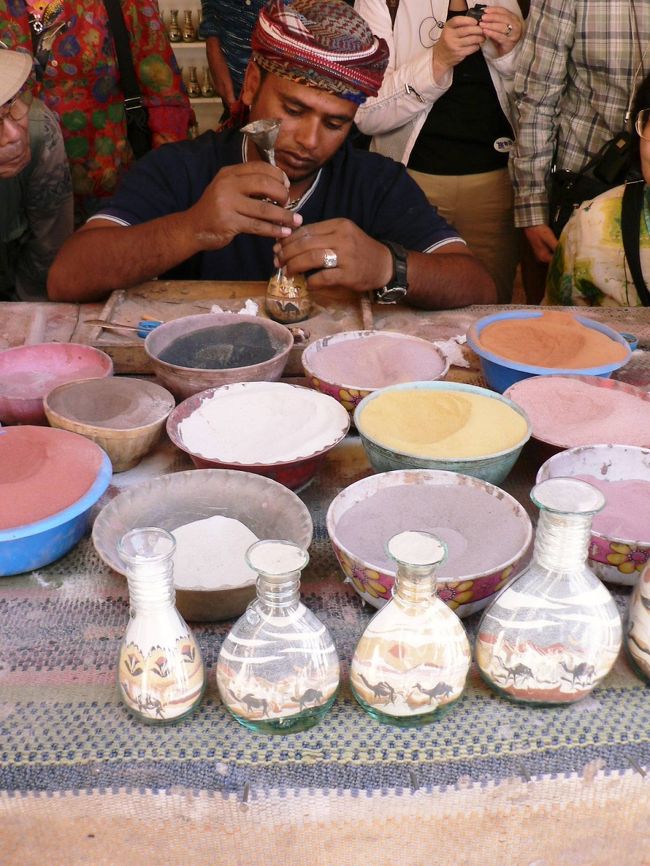 壷に砂絵を描くベドウィン族の男性。