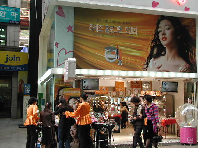 化粧品ショップ店頭での「メーカーデモンストレーション」！お揃いの制服で、「メイクアップキャンペーン」を通行女性にアプローチ！<br />座ると直ぐに「人だかり」が．．．<br />日本では「２０年前のやり方」韓国女性の化粧意識は「ナチュラル＆素肌美中心」<br />メイク女性は少ないだけに、日本もそうですが「メイクによる変身」から．．．化粧意識アップに！