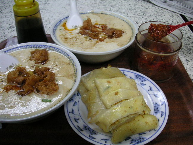 片言の日本語でおばちゃんが「アマイノ？カライノ？」と聞いてきます。<br />甘いのは砂糖をいれた豆乳。カライノは干しえびやザーサイ、ラー油などで味付けしたおかず風な豆乳です。<br />ななとものチョイスは毎回「カライノ」。<br />そして蛋餅という卵をもちもちの皮で巻いたもの。これに豆板醤をつけると最高だよ。