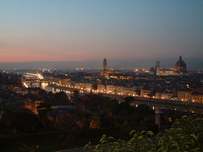 広大なピッティ宮を眺め、再びアルノ川河畔へと戻り、今度はミケランジェロ広場を目指して歩く。<br />この広場は高台にあり、ドゥオモを含めたフィレンツェの街全体が見渡せるビュースポット。<br />せっかく登るなら夕景から夜景が見渡せる時間に登るのがベストなので、17時頃の到着を目指した。<br />ちょうど頂上にたどり着いた頃には、薄く夕靄が街を覆い始めていた。<br />だいぶ歩き疲れたので、ジェラードを食べながら、街に灯りが灯るまで暗くなるまでしばし休憩する。<br />15分ほど過ぎて、少しずつ空が濃度を増し、街にはオレンジ色のガス灯がちらほらと灯り始めた。<br />夕焼けに照らされた姿も美しかったけど、夜景はさらにロマンティック。<br />遠くから聞こえる教会の鐘の音が、郷愁をさらにかきたててくれた。<br /><br />＊ミケランジェロ広場への行き方のおすすめルートは、アルノ川左岸をずっとまっすぐ進み、<br />行き＝セリストーリ宮の城門から階段で登る。<br />帰り＝いろは坂のような長いヘアピンカーブの坂道をゆっくり下り、ポッジ広場に出る。<br />というもの。後者の坂道を上るのは結構辛いので、登るときはショートカットを利用し、帰り道で良い景色を長く楽しみながらのんびり坂を下るのがベストだと思いますよ。