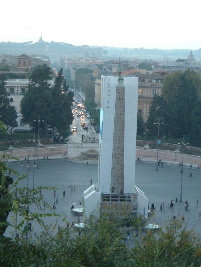 ピンチョの丘までたどりつき、見下ろすとポポロ広場のオベリスクは修復中だった。<br />それでも、写真でラッピングした囲いをつける努力に感心。<br /><br />だんだん暗くなっていく街並を見下ろしながら、再びスペイン広場まで戻り、この日の観光を終了した。