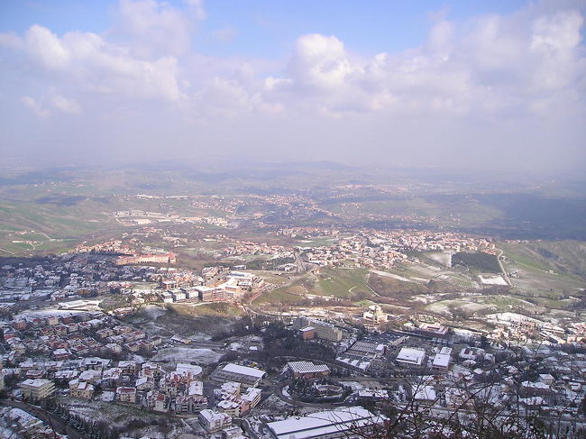 ティターノ山麓のバスターミナルに到着。雪が５〜１０センチくらい積もってました。ただでさえ興奮しているのに、１週間前のオーストリア以来の雪にさらにわくわく。足下に気をつけながら、うねうね蛇行する道を行きつ戻りつ、市街地を通り抜け、東側の高台に立ちました。そしてこの景色！眼下に所々雲の陰になっている街が広がります。雲が近いです。