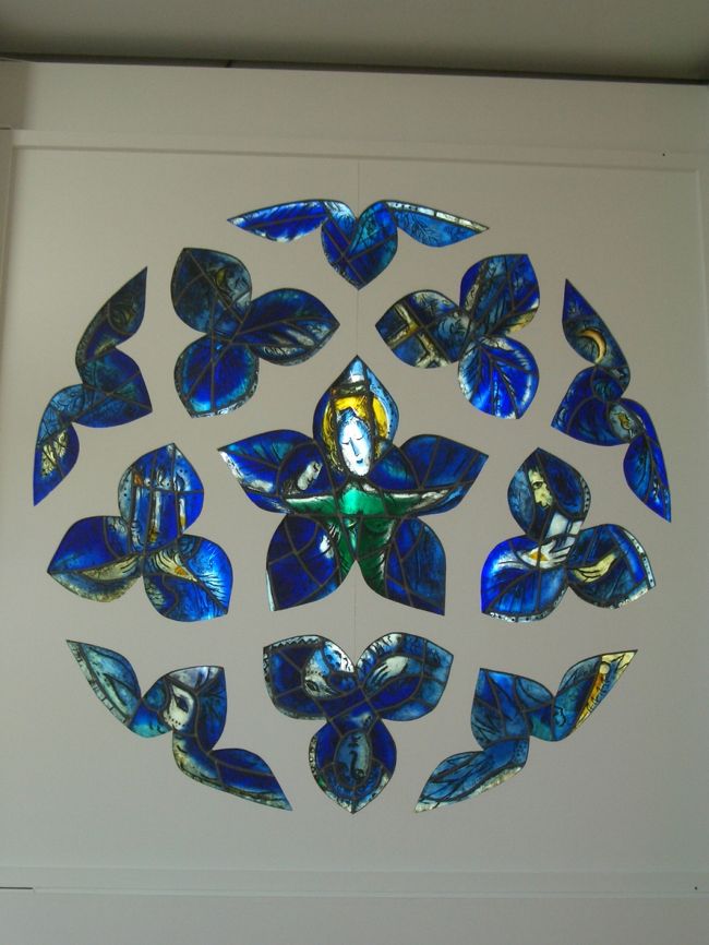 同じくシャガール美術館の、ステンドグラス。<br /><br />このシャガール美術館でもマティス美術館でも、ガイドの説明をしっかり聞くことができて、とても充実していた（ツアーの恩恵ですね）。<br />特にシャガールの方は宗教画美術館なので、宗教に疎い私が見ても「きれいな青ね」ってなモンなのだが、宗教にまつわるその絵の説明を詳しくしてもらうと、その絵を何倍も楽しむことができる気がする。<br /><br />で、そのガイドによると、この美術館はシャガールの存命中に建てられシャガールもその建設に関わったので、シャガールの思い入れを随所に見ることができる。<br />このステンドグラスもそのひとつで、太陽の光が差してくる場所を選んで、この壁に設置されたそうな。