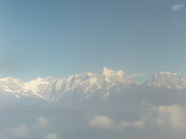 ルクラまでの飛行機の席は乗った取ったモン勝ちなので、一番に乗り込んでガイドのアドバイスどおり左側の席を確保。<br /><br />左の窓からはカトマンズ近郊にある寺院ボダナートや雪の積もった山脈が見える。（右側はたいしたものは見えない）<br /><br />写真は色がくすんで見えるがこれは空が霞んでいるのではなく飛行機の窓が汚れているため。残念。