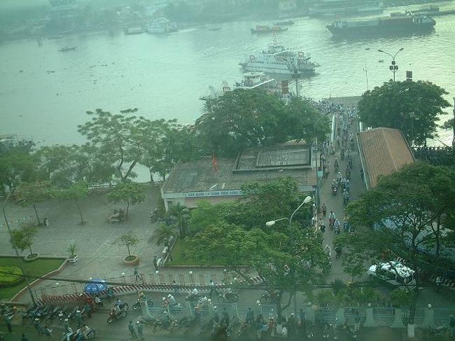 ホテルの窓より。<br />対岸より渡し船が着いて、通勤通学のバイク・自転車の群れが流れ出てきました。出口付近にはバイクタクシーがたくさん待機していて徒歩のお客さんを乗せて行きます。<br />白いアオザイ服の女学生さんたちもいます。