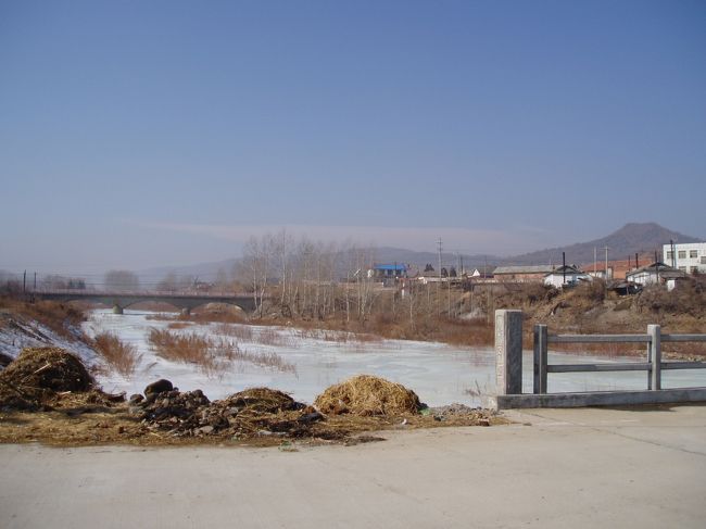 天佛指山（１２６５メートル）と呼ばれる山から流れ出る水が川（写真）となり三合地域の図們江へと流れ込みます。<br /><br />遠くに見える橋を左へ直進すると三合口岸です。現在立っているこの道を進んでも口岸にたどり着けます。