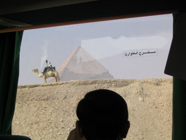 車窓から。カフラー王のピラミッドとラクダ警備隊。バスの窓のアラビア語は「非常口」と書かれてる？