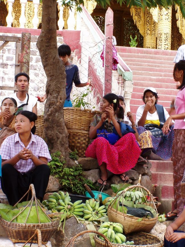 　１時間あまりで神殿のあるタウンカラッの麓に着いた。ドライバーがつきあっている彼女は、神殿への階段の入り口の隣に小さな茶店を構えていた。ドライバーが旅行者をここへ連れてくる度に彼女の茶店に寄り、親交を深めて行ったのだろうか。当の彼女は女子プロレスラーの北斗晶をふくよかにさせたような感じだった。２人並んで座っているのを見ると、実に仲が良さそうで、微笑ましい印象を受けた。二人の見送りを受け、僕は神殿への長い階段へ向った。<br />　鉄の階段は長く、急で、けっこうきつい。猿があちこちにいて、観光客があげる餌を食べていた。餌は売店で売っていて、新聞紙で筒状に包まれている。当然猿はそれを破って食べるから、あたりは新聞紙の破片だらけだ。猿は日本の観光地にいるような、観光客に暴虐の限りを尽くす不良猿ではなく、餌をくれない人には基本的に無関心だった。参道だから裸足で歩くのだが、周囲に猿の糞が落ちていて汚い。いつ踏んでしまうとも限らず、絶えず足元には注意が必要だ。それにしても、くそ猿どもの糞が落ちているようなところをなぜ人間様が裸足で歩かねばならぬのか。ミャンマーの精霊様は理不尽な業をお課しになるものだ。おまけに糞の臭いが臭いんだよ。当たり前だけど。<br />　参拝者はミャンマー人ばかりで、バガンの寺院とは違って地元の人たちの観光地という感じ。階段の所々に小さな売店があり、どこでも見かけるようなだるまさんやふくろうの置物を売っていた。<br /><br />写真は、階段への入り口にたむろする売り子たち。
