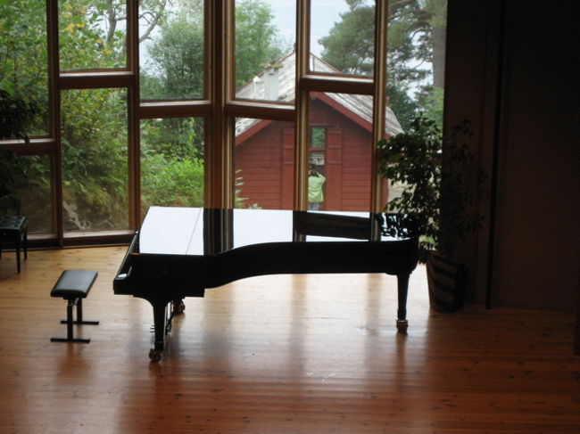 今夜の準備でしょうか、、、。ピアノが舞台に置いてありました。窓のむこうにはグリーグの作曲小屋とフィヨルドの水辺が見えます。