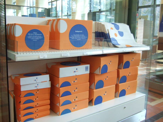  教会かたテクテク歩いてみると、駅は結構近くでした。こんなことなら最初から歩けばよかった。。<br /><br />　駅横の郵便局へ。<br />　日曜日なので郵便業務はやっていませんでしたが、カードやフィンランドみやげなどは販売中。<br />　それにしてもカードの数がすごい！<br />　みんなまめに書くんですねえ。<br />　<br />　ここではムーミンやアーリッカなどのお土産も買えます。○ちゃんは、ムーミンの今年の限定品がここにしかないかもしれないと早速購入（結局、ストックマンとか他の場所では見つけられず、買って正解だったようです）。<br /><br />　私はサンタさんの切手帳とムーミンの携帯ストラップ、おしゃれな紙袋を購入。<br />　<br />　写真は、よくあちこちの旅行本で紹介されている郵便局のグッズ。ポストも郵便自動車も、このオレンジ色に青のデザインで統一されています。小包の箱も袋もおしゃれです。