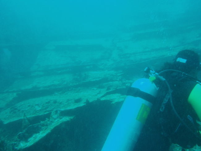 オガタ丸の一部。手前はガイドのTonです。沈船といっても原型をほとんど留めていないため、大きな鉄くずにしか見えません。