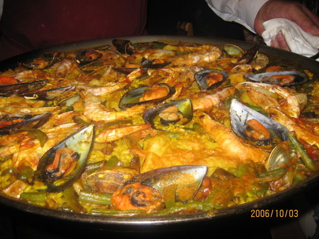 スペイン名物パエリア。　サフランで黄色く色付けされたご飯に、今回はシーフードパエリアなのでエビ、アサリ、ムール貝、イカなどと野菜がのっていました。