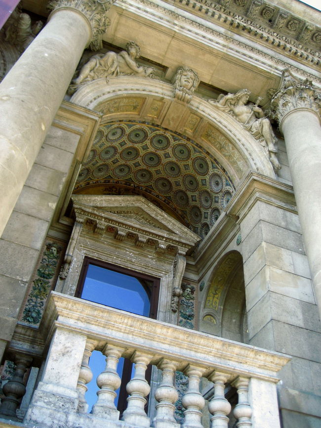 国立オペラ座の正面テラス<br /><br />内部ガイドツアーでは写真は撮らせてもらえませんでしたが、途中で正面のテラスに出たときは、外側の写真は撮り放題でした。<br /><br />内部は確かに豪華でした。一部アール・デコ風なのも、リフレッシュされたかんじでなかなかいいです。<br />修復された後なのでやや新しく見えるところがちょっとモノ足りませんでしたが、豪華さにはううーんとうなりました。<br /><br />ここからはガイドから聞いた話です。<br /><br />このブダペストの国立オペラ座には、皇妃エリジュベートは何度も足を運びましたが、皇帝は一度しか訪れませんでした。<br />その理由は、皇帝自身はオペラは好きではなくて、すぐに寝てしまうくらい退屈してしまうせいもあったようですが、ウィーンのオペラ座よりも豪華だったのが気に入らなかったという説もあるとか。<br />質実剛健を好む皇帝は、もともと装飾過多な内部も好みではなかったようです。<br />なので皇帝・皇妃のロイヤルボックスは彼らのために一度しか使われませんでした。<br />というのも、当時は皇妃だけが一人で訪れたときには、ロイヤルボックスは使わせてもらえなかったからです。<br />そのため、彼女は別の場所に席をとりましたが、好んでとったボックス席はいつも決まっていました。<br />しかし、その席は、ボックス席の中では安い部類に入ります。<br />なぜなら、１番舞台に近い脇の席で、舞台はとても見づらいのです。<br />むしろ彼女は、自分の姿を観客に披露するために好んでその席をとったといわれています。<br /><br />また、このオペラ座は建物は相当な規模なのですが、客席数は1,342席しかありません。<br />ウィーンのオペラ座の2,000席より多くすることはできませんでした。<br />代わりに舞台のスペースがとても大きくて、例えば「アイーダ」のような大掛かりな舞台装置を必要とするオペラにはおあつらえむきだそうです。<br />それを聞いて、10月15日に観劇予定の「バンク・バーン」の舞台装置も期待できそう、と今から楽しみになりました。<br /><br />オペラ座のシーズンは９月〜翌年の６月までと長いです。<br />チケットはウィーンや他の名高いオペラ座に比べるとずっとおトクな値段だそうです。<br />私がとった「バンク・バーン」のチケット代は、ロイヤルボックスを除いて上から二番目くらいの値段のカテゴリーでしたが、6,500フォーリントでした。<br />（2006年10月現在、1フォーリント＝約0.6円）<br />ただし、チケットの価格でもっとぶっとんだのは（驚いたのは）、ルーマニアの首都ブカレストの国立オペラ座です（週末の割高値段で１番高い席で日本円にして900円かかりませんでした）が、その話はまた後日@<br /><br />オペラ座ではバレエも上演するし、オペラは必ずオリジナルの言語で上演されて、字幕も出るそうです。<br />そうか、「バンク・バーン」も字幕で観劇できるのね！<br />と、一瞬、喜びましたが……よく考えたら「バンク・バーン」はハンガリーのオペラなのでハンガリー語で上演されます。<br />たとえ字幕があってもハンガリー語だとしたら私には無用の長物ですなぁ。<br /><br />オペラ座は第２次大戦中にかなり破壊され、いまでも修復中だそうです。<br />ガイドツアーではその中でもきれいに修復されているところを中心に案内してくれました。<br />規模の大きさがたたって、修復にお金と時間がかかっていてなかなか進んでいないそうです。<br />オリジナルの装飾を復元するにも、当時と同じレベルの技術を持つ技術者やアーティストを集めるのが困難で、たとえば内部の壁画など、レベル落ちは免れないのだとか。<br /><br />説明を聞いているときに写真を撮りたくてうずうずしましたが、大丈夫、観劇のときに撮れるので、そのときを楽しみにしましょう。