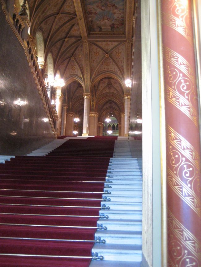 国会議事堂内部<br /><br />この階段を上るところから見学開始です。<br />柱の金の模様もなかなか素敵です。<br /><br />ちなみに、国会議事堂はハンガリー語でOrszaghaz（オルサーグハーズ）といいます。<br />ハンガリー語ってむずかしいです。<br />ヨーロッパ語系ではないので、英語だのフランス語だのドイツ語だのの単語からの連想がきかないのです。<br />ソ連支配が長かったため、発音さえ聞けば、ロシア語と似ているのはないこともないですが。<br />このOrszaghazという単語も、どこで区切ってよいか、最初はさっぱり分かりませんでした。<br />連想できる似た単語なく、まるで記号のようです。<br />おかげで、オルサーグハーズなのかオルハーグサーズなのか、何度も混乱し、なかなか覚えられませんでした。<br />末尾のhazが要するにhouseという意味らしいということに、２年前の2004年の初ブダペストの最終日（５日目）にして、やっと気付きました。<br />なので今回は大丈夫です@<br /><br />でも。。。ブダペスト観光をしていると出会うたいていの人は英語が通じますから、Parliamentですんでしまいますけどね。