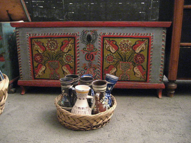 民族博物館の新婚さんの家財道具<br /><br />Kalotaszegというところは、1850年代から美しい木彫りや板絵や木彫りの縁飾りで有名だったそうです。<br />そして結婚式のときに、新婚さんが教会で式を挙げている間、新婚さんの親たちが新婚さんの家財道具をこのように村の人々に披露する習慣があったのだそうです。<br />その中の模様が見事な家具をメインに撮りました。<br /><br />民族博物館に保存されていたのは、ハンガリーのトルコ支配が終わった後の18〜19世紀くらいの各地の民衆の生活というところでしょうか。<br />「地球の歩き方」をもう一度ひっくり返してみると、民族衣装や家具の展示はどうやら現ルーマニアのトランシルヴァニア地方のものでよいみたいです。<br />見れば見るほど花の刺繍や模様に溢れた可愛らしい生活環境でした。１つ１つ時間をかけて丹誠に作られたものばかりで、このように一瞬にしてカメラに収められるようなものではないだろうなぁと思いました。<br />生活を楽しむ術を知っていたというよりは、地に足の着いた生活を感じさせました。<br /><br />でも、うらやましいかと思うと、そうはとても言えません。<br />すでに娯楽や刺激が多く、物流の流れが激しい消費時代の今を楽しんでしまっているので。<br />当時は豊かではなく、生活が苦しかったわけですから、たまにであれば心を癒すのにいいかもしれないけれど……。<br />これって易きに流されているということかもしれませんね。