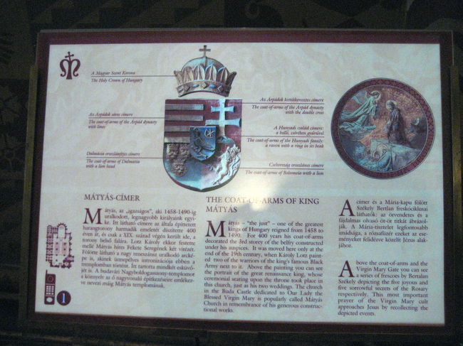 マーチャーシュ教会にあった紋章の説明<br /><br />これは入ってすぐ左手の壁にありました。<br />紋章学についてそれほど詳しくないし、凝っているわけではないですが、意味が分かるのは楽しいです。<br />それに、今回は、教会の名前となっているマーチャーシュ・コルヴィヌス王の紋章を見つけたいと思っていました。<br />コルヴィヌスのコルヴィンは烏の意味で、マーチャーシュ王の紋章は大ガラスが指輪をくわえたデザインなのだそうです。<br /><br />その紋章に近くにこの解説がありました。<br />大ガラスの紋章は確認できましたが、これを読んでいて、私が１番関心を覚えたのは、右上の十字の変形（ダブルクロス）の紋章です。<br />これはイシュトヴァーン王から300年続いたアールパード家の紋章だったのですね。<br />ただ、左上の、地が赤に白い三本線もアールパード家の紋章のようです。<br />どう使い分けられたのかしら。<br /><br />右下のライオンは、ボヘミア王、すなわちチェコ王家のものです。<br />確かにハンガリー史をひもとくと、アールバード王朝が断絶した後にハンガリーを支配した王の中にルクセンブルグ家のジグモント王がいて、彼はドイツやチェコの王も兼ね、神聖ローマ皇帝の地位にも就いています。<br />ちなみに、チェコ史とのかかわりでいえば、宗教改革の先駆けのヤン・フスを処刑したのはこのジグモント王です。<br />マーチャーシュ王の紋章にボヘミアの紋章が合体しているのは、彼がオスマン・トルコをハンガリー南部でそれ以上の侵入を食い止めた後に、チェコとモラヴィア地方を占領したからでしょう。<br />マーチャーシュ王は一時、ウィーンも占領して手中に収めています。<br />彼はルネサンス君主として有名ですが、領土の規模でいっても、ハンガリー史の最盛期の１つを謳歌した王といえましょう。<br />マーチャーシュ王は在位1458〜1490年の王なので、西欧諸国は、まだまだ後進国だった時期です。<br />東欧諸国はこのように西欧より先に時代の栄華を極めたのですが、その後、それまで後進国だった西欧諸国に追い越されてしまうのです。<br /><br />左下のダルマチアは、現クロアチアのことですね。<br />ハンガリーがクロアチアの地を失い、クロアチアが独立を果たしたのは、第一次大戦後の1920年のトリアノン条約によってです。<br />ちなみに、トリアノン条約によって、ハンガリーはクロアチアだけでなく、チェコにもルーマニアにもスロヴァキアにも領土を割譲させられます。<br />その結果、ハンガリーの領土は３分の１になってしまいました。<br />その失われた領土を取り戻してくれるとの約束を当てにして、第一次大戦のときにはナチス・ドイツ側につくのです。<br />それに比べ、今回の旅行先のルーマニアは、近代までの歴史はハンガリー史に比べるとパッとしない印象があったのですが、２度の大戦で結果的にどちらも戦勝国側についていました（正確には、第二次大戦時は、途中から連合国側につきました）。<br />たとえは悪いですが、ハンガリーはどちらも賭けに負け、ルーマニアはどちらも賭けに勝ったといえるのではないでしょうか。<br />この対比もなかなか興味深いと思いました。<br /><br />マーチャーシュ教会の外観の写真は撮りませんでした。<br />修復中で外側が一部、工事用のプレハブで覆われていたりして写真映えしそうになかったのです。<br />それに2004年に撮っているので、撮らなくていいやと思いました。<br /><br />内部の写真も、あんまり薄暗いので、さすがにデジカメでも良く写りそうにないのでやめました。<br />全体的な雰囲気には再訪でもとても感動したのですが、それはとても写真には収めきれません。<br />かえって、感動した美しい記憶が損なわれるだろうと思いました。<br /><br />マーチャーシュ教会の外観の写真は、２年前のものをご覧ください。<br />屋根はきっとジョルナイ・タイルでしょう。<br />初めて訪れた衝撃と感動のため、感想も２年前の方が詳しいです@<br /><br />関連の写真<br />http://4travel.jp/traveler/traveler-mami/pict/10505094/<br />関連の旅行記<br />http://4travel.jp/traveler/traveler-mami/album/10038942/