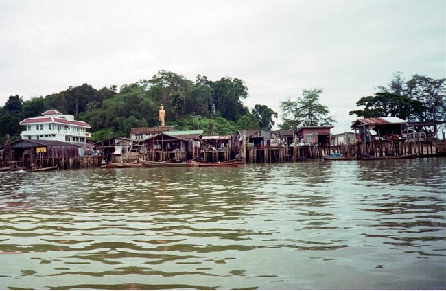 ミャンマーに渡る小さい舟は横に揺れると倒れそう。<br />川岸にはこんな感じの家が立ち並んでいる。