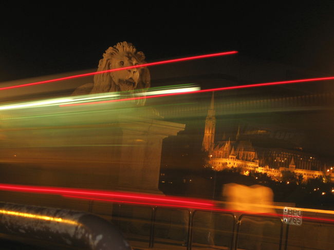 鎖橋のライオン像<br /><br />おっと、セルフタイマーにしていたら、撮影の瞬間に、目の前をバスが走り抜けてしまいました。<br />しかし、夜景用のスローシンクロモードだと、走り去る車のライトはこのような光のラインのように写るのですねぇ。<br />いや、プロの街の夜景写真を見て、そのこと自体は知っていましたが、あれはプロが扱うしっかりとした一眼レフカメラではないとならない現象かと思っていました。<br />デジカメおかげか、私のコンパクト・カメラでもこのような写真が撮れるなんて！<br />妙に嬉しくなったので、これはこれでとっとくことにしました。<br />これはこれで面白いですしね@