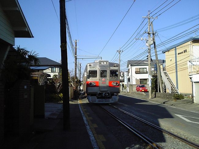 路面区間の北半分では、西側の路肩は人一人がやっと通れる程のスペースしかない。<br />「民家の軒先」を走る電車は少なくないが、ここでは「民家の玄関先」を走っている。