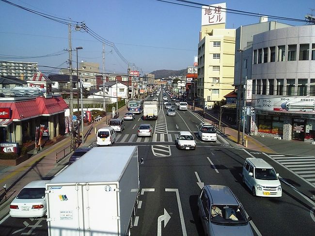LRT化案は、大雑把に分けると2通りの案がある。<br />第1案は、北熊本駅の南側で国道に入る案。<br />第2案は、藤崎宮駅付近から国道に入る案。<br />国道では、現在バスレーンとして利用されている車線に軌道を敷設する案が最も現実的なようだ。<br />写真は黒髪町駅付近の国道3号線北方向。<br />この区間は片側2車線でバスレーンも確保されていないので、第1案を採る場合、道路の拡幅と同時に行なわなければ電車を利用しない市民の理解を得るのが難しそうだ。