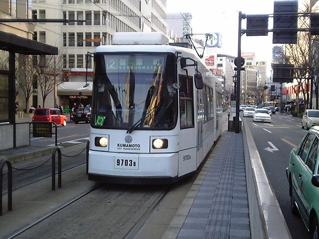 LRT化案では、国道3号線と路面電車が交差する水道町で路面電車に乗り入れることになっている。<br />水道町交差点は、既に都会の街並み。<br />ここから路面電車に乗ってみた。<br />乗車したのは新型の低床電車。<br />日本で最初に低床電車を導入したのは、ここ熊本。<br />意外と知られていないが、熊本の路面電車は日本で最初にVVVF制御電車を導入するなど、かなり先進的。<br />低床電車には「パーサー」と呼ばれる車掌が乗務しており、前後どちらの扉からも降車できた。<br />車内は意外と狭く、混雑が目立つ。<br />いくら低床にしても、車内が常に混雑しているようでは利用しにくい。<br />熊本の路面電車は非常に運転間隔が短いので、広島のように多少電車を間引いても大型車両を入れることを考えても良さそうだ。<br /><br />熊本の路面電車は、乗車距離によって運賃が変わるバスのようなシステムだが、丁度均一運賃の社会実験を行なっていた。<br />乗車区間に関わらず150円、というものだったが、私が乗車した水道町〜水前寺駅通間は、本来なら130円の区間なので、かえって損だった。