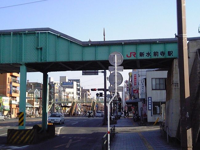 水前寺駅通で路面電車を降りる。<br />その名の通り、豊肥本線水前寺駅の最寄停留所だったが、JRが路面電車との交差部近くに新駅「新水前寺駅」を開業させ、さらに乗継が便利になった。<br />しかし、停留所名が「“水前寺駅”通」のままなのは、どうかと思う。<br />地元客以外も利用することがあるのだから、「新水前寺駅前」などに改称した方が分かりやすい。<br />また、停留所の位置もやや中途半端。<br />JRの跨道橋直下に移設して、直接JRホームに行けるような設計にしておけば、かなり便利になったはず。<br /><br />写真の真中奥に小さく見える歩道橋下が水前寺駅通停留所。<br />跨道橋手前右側すぐの所にJR新水前寺駅の入口がある。<br />実際、路面電車を降りた乗客のうち何人かはJR駅に向かっていた。
