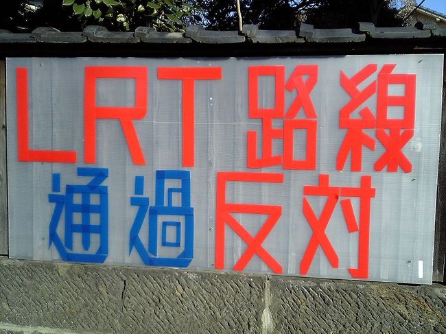 第2案最大のネックは黒髪町駅〜藤崎宮前駅間の路面区間が解消されないことだろう。<br />実際、路面区間には写真のような看板が大量に掲示されていた。<br />現状でも大型の電車が毎時4本通過する危険な場所なので、これ以上電車を増やして欲しくはないのだろう。<br />運転上も、LRT化するなら最低でも毎時4往復の運転が必要だが、単線運転ではギリギリ。<br />この区間は民家の軒先を走るので、複線化も現実的ではない。<br />LRT化も容易ではなさそうだ。