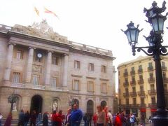 １１：５９
サン・ジャウマ広場 Placa de Sant Jaume。

「　サン・ジャウマ広場 Placa de Sant Jaume　」 を囲んで
向かい合って建つのは 「　市役所 」　と 「　カタルーニャ自治政府庁　」 。

「　サン・ジャウマ広場　」　は、現在のカタルーニャの政治の中心。　

「　市役所　」　の建物自体は１４世紀に完成され、正面部分だけは１９世紀に改築されたもの。

「　カタルーニャ自治州政府庁　」　は、１４世紀の建物をそのまま使っている。　正面は１７世紀のもので、中にあるサン・ジョルディの礼拝堂とオレンジの庭はカタルーニャ・ゴシック様式。