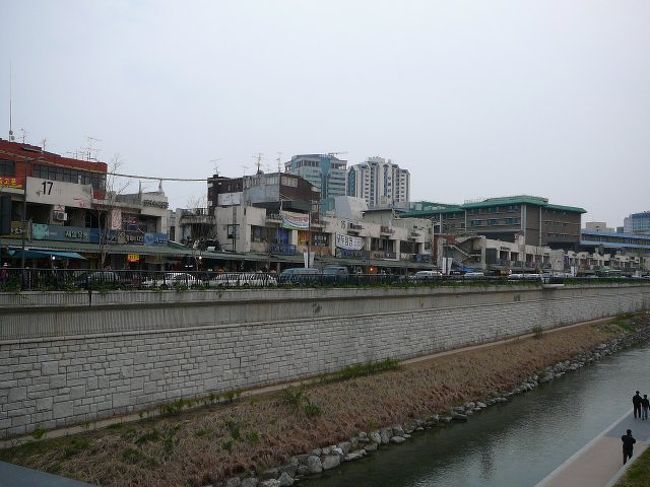 東大門の先に連なる長屋式？お店の長さ・・下のほうにグリンがかった軒先が続いているのが分かりますか？本当に間口が二間あるかないかの小さなお店が、いくつも、いくつも、いくつも！連なっています。<br />靴屋さん、ベルトやさん、電気屋さん、中古パソコンやさん、アダルトやさん・・・なんでもかんでもあります。建物はかなり古いようでした。どこまで続いていたのか、途中であきらめて、フリーマーケット？の方に移動したので、終点？はどこなのか分かりませんでした。