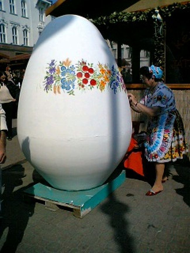 民族衣装を着た女性がイースターの卵にペイント中。