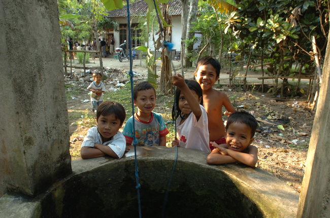 井戸の水汲み場で家人の手伝いをする子供たち