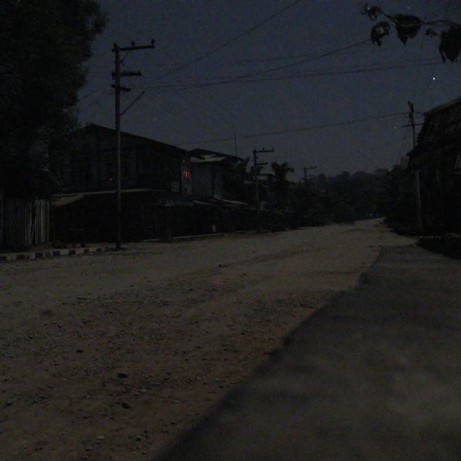 踊り手さんたちの出番が終わると、多くの人が帰り始める。<br />しばらく居続けたけど、僕も途中退席させていただく。<br /><br />帰り道。月明かりに白茶けた道路が光って、まるで雪道を歩いているよう。<br />ぼんやりと道が白くほのめく。<br />ゲストハウスまでの道のりで、動いているのは僕と川だけ。<br /><br />この写真がその帰り道です。<br />ここは市場の前で、ミャウーで一番の中心街。<br />Exif情報を見ると、22時04分04秒撮影、露光8秒。<br />雰囲気が伝わればいいんだけど。<br /><br />ベッドに入ると、まだ続いているコンサートの音が聞こえてくる。<br />1km以上は離れているはずなのに、静かに、でも妙にくっきりと、まるで耳元で鳴っているように。<br /><br />近くで聞くPAの音質は、音割れドンシャリで酷いものだったけど、遠く離れてベッドに横たわって聞く音は、子守唄のように安らかな音質だった。