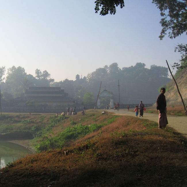 シットウェーで色々な人々出会う中で、ミャウーに行ったらぜひ行ってみろと薦められたのが、『バンドーラ(Bandola)僧院』と『コータウン(Kothaung)寺院』。<br /><br />起きるのだけは早い僕は、朝もやの中、前者のバンドーラ僧院へ向かう。<br />Royal Cityゲストハウスから、中心街へ向かう橋を渡らずに手前を右に曲がり、道なりに進み、この写真の突き当たりの参道を登ってゆく。<br /><br />ごめんなさい。<br />ミャンマーの方々が僕に薦めてくれる場所は、観光の場所というよりは、仏教的に大切な場所、自分が行ったら真っ先にお参りしたい場所、という場合がある。<br />それはとてもありがたいことです。<br />正直に言います。ここには特別に見どころはありません。だってここは僧院で、修行と祈りの場所だもの。外国人はほとんど来ません。<br /><br />そんな僕でも、僧院の方々は歓迎してくださり、お祈りとお布施が終わって帰ろうとするころ、シットウェーからの船に同乗していた学生たちと出会いました。<br /><br />彼らもまず最初にバンドーラ僧院に参拝しようとしたら、外国人の僕が自分たちより朝早くに参拝していたことに驚き、感激したようです。<br />誤解です。でも訂正しないのを許してください。<br /><br />それからは街で出会うたびに、より親しく呼びかけられるようになり、『15世紀に日本のサムライがやってきて、アラカンの2人の王のボディーガードを勤めたんだ。アラカンと日本には長い歴史があるんだ』なんて言われたり。<br />伝説です。でも信じてもいい。<br /><br />(後日談 : 見所はあります。参道を登る前を右に曲がって登っていく丘陵には、仏像が立ちならび、そこからの夕陽は格別でした)