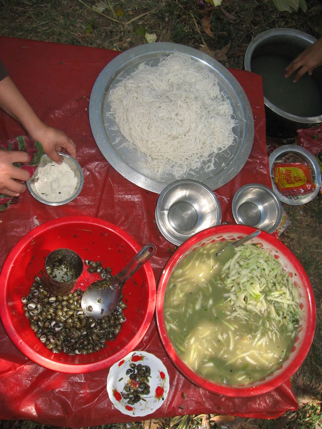 貝の出汁に大根(のようなもの)の千切りを入れ、塩と唐辛子で味を調えた冷たいスープを、そうめん(のようなもの)にかけたもの。出汁をとった後の貝付き。<br /><br />めちゃくちゃ旨い。<br /><br />とりあえずは大丈夫だったけど、お勧めはしません。<br /><br />僕の胃腸はごく普通で、あんまり強くないです。<br />旅行中はせめてがんばって欲しくて、腸内細菌を応援する乳酸菌錠剤を旅行前から飲んできたおかげで、お腹を下す事はほとんどなく過ごせました。<br /><br />でも寄生虫となると話は別で、ただ運が良かったんだと思います。茹でているところ所を見ずに淡水貝を食べたのは、今思えば軽率でした。<br /><br />でもめちゃくちゃ旨かった。<br />普通のレストランではメニューに無いんだよなぁ。