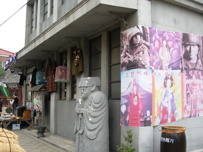 本通りから、脇道に入った場所です。壁にべたべたとポスターが貼ってありました。その入口には、済州島の石のおじさんらしい像がありました。