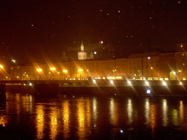 ザルツァッハ川の対岸から見た旧市街の夜景です。川面に反射したオレンジ色の明かりと舞う小雪が幻想的な雰囲気を醸し出していました。
