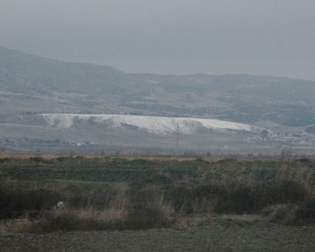 パムッカレの石灰棚が山の中腹に白く見える。綿畑には綿の実が付いた幹が残っていた。<br />ガイドは結婚適齢期の娘さんがいる家にはガラス瓶を屋根に載せておく風習が残り、実際に載せた家が見られたが、この風習が廃れつつあるのも無理からぬことである。