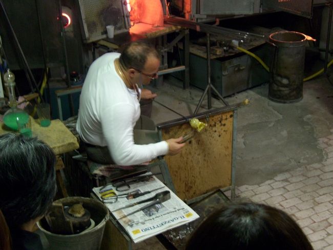 ベネチアングラスを作っているところを見学しました。<br />3月でまだ少し肌寒い感じでしたが、工房の中は暖かかったです。<br />夏は作業大変でしょうね。<br /><br />それにしてもこの人なぜかものすごくマッチョ。<br />ベネチアングラス作るのって力が必要なのかな？