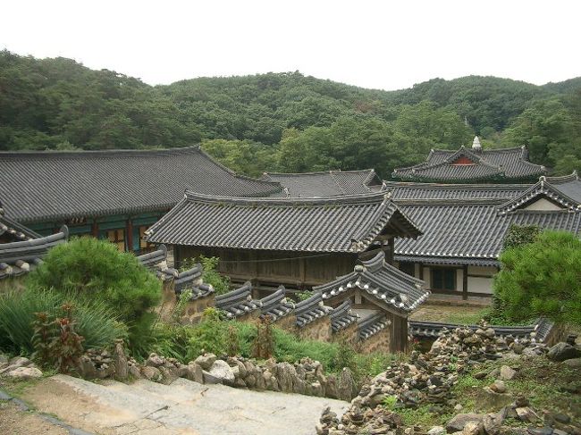 うえから、寺の敷地を見渡します。<br />小ぶりの建物がいっぱい建ってるのが、韓国のお寺の特徴でしょうか。<br /><br />ヨシ！<br />見るもの見たし、帰ろう！<br />お母さんもお腹が空いてきたようです。<br /><br />駐車場にもどると、バス停とおぼしき看板と駐車スペースはあるのですが、いつになってもバスがやってきません。<br />小雨も降りだし、途方にくれます。<br />やばいよ、タクシーも通らない・・。<br /><br />駐車場の角にあるレストランへ入り、従業員の女性に筆談で「タクシー呼んでもらえますか？」と聞いてみます。<br />突然で失礼な申し出ですが、会話ブックでの用例集なんて、要求とクレームのつけ方くらいしか載ってないので、多少は大目に見てください。<br /><br />「そこに座って待ってて。いま呼んだから」<br />と、言ってくれているものと思われるので、お母さんとならんで、座って待ちます。<br />単語だけなら何とか分かる会話で、親切な従業員の人とコミュニケーション。<br />「イルボン（日本）から来た」<br />「アクセサリーがイッポ（可愛い）」<br />銀政が聞いたら大笑いしそうですが。<br />銀政からは、スラングしか習わなかったんだもーん。しょうがないじゃーん。<br />人懐こい女性で、なんのかんのと話し掛けてくれます。<br /><br />軒の向こうでは、さらさらと霧雨が舞っています。<br /><br />